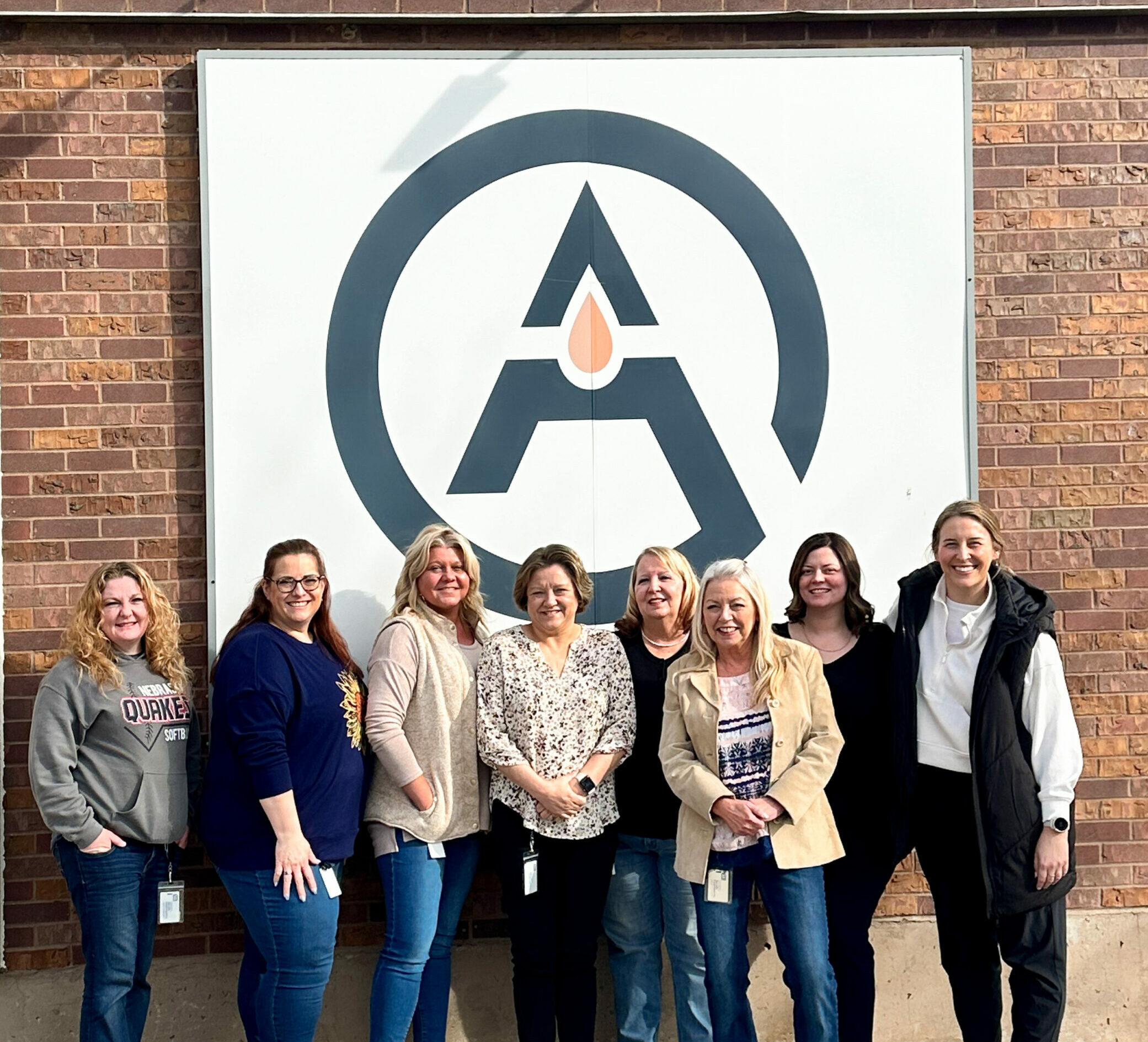 Group of employees standing outside of a brick office building